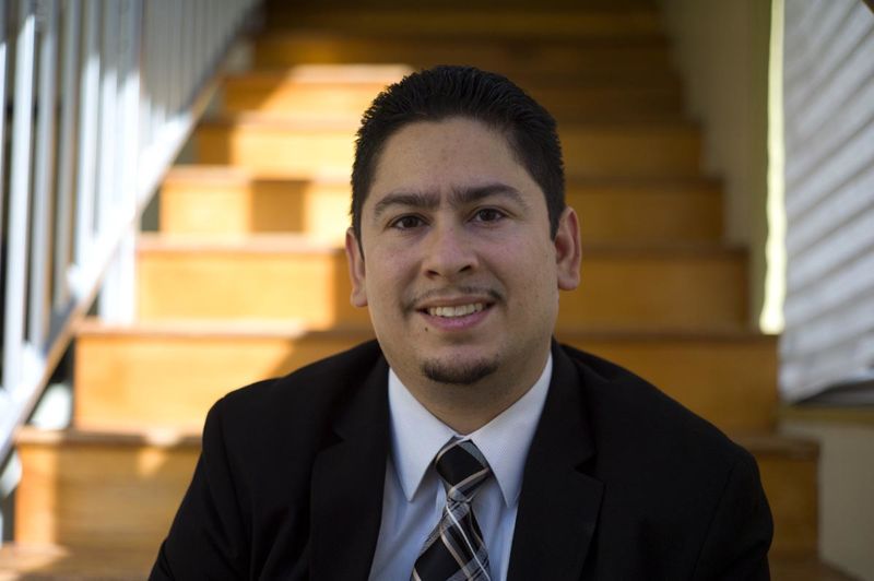 A man in a suit poses for photograph on a flight of stairs.