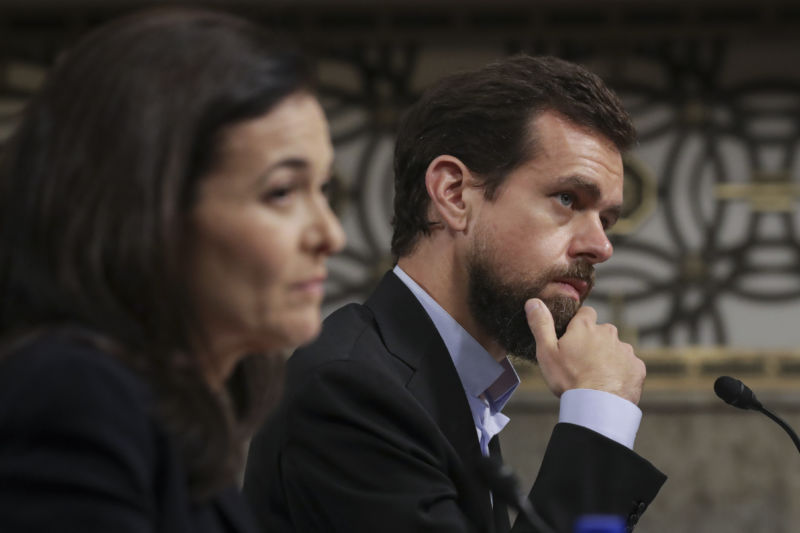 Two people in business attire listen intently.