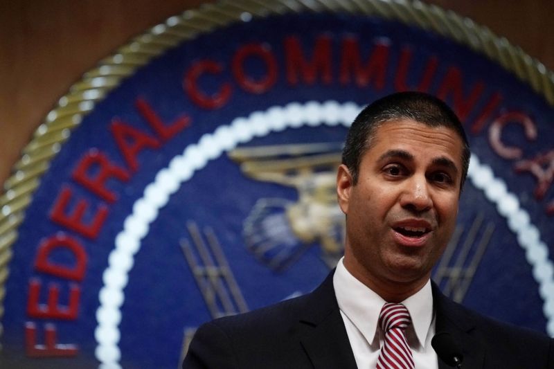 FCC Chairman Ajit Pai standing in front of the FCC seal and speaking to reporters.