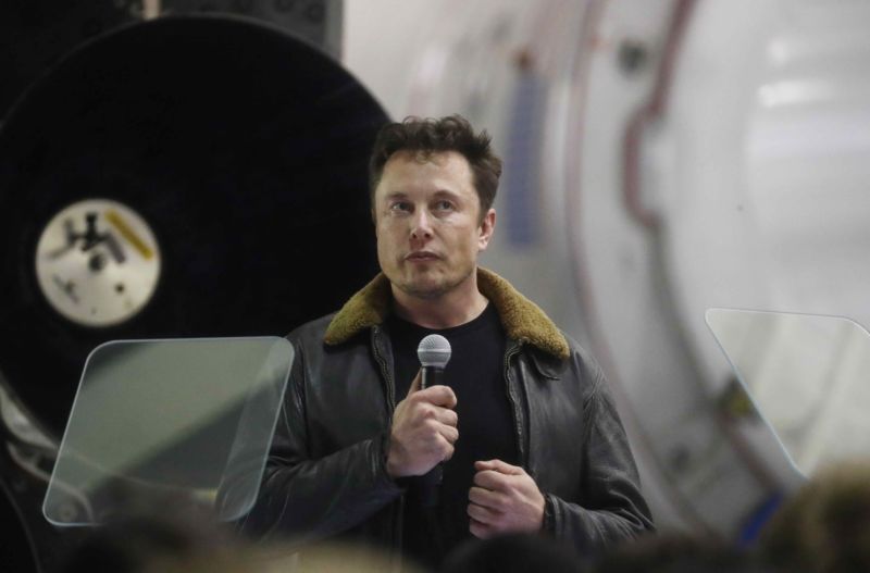 SpaceX CEO Elon Musk standing and holding a microphone.