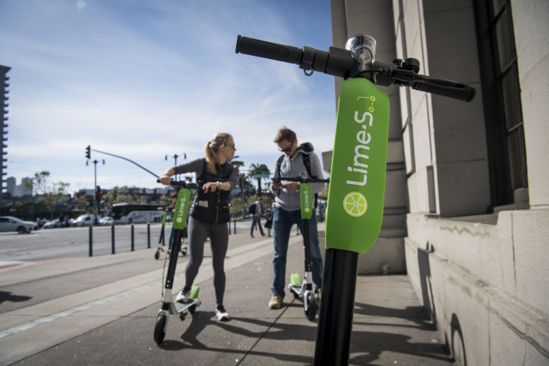 People use a smartphone to unlock a LimeBike shared electric scooter on the Embarcadero in San Francisco, California, on Thursday, May 3, 2018.