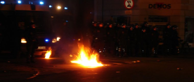 Image of a fire burning in front of riot police.