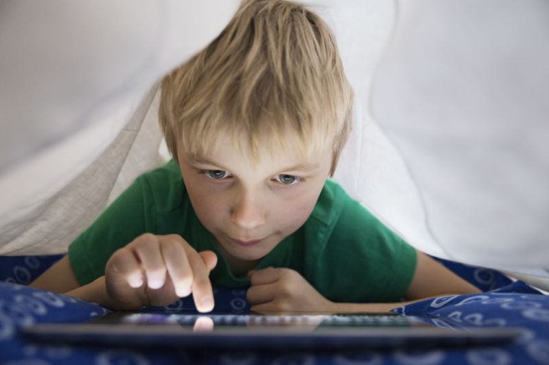 A boy tapping the screen of a tablet computer.