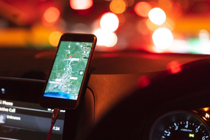 A smartphone displaying a map while propped up on a car dashboard.