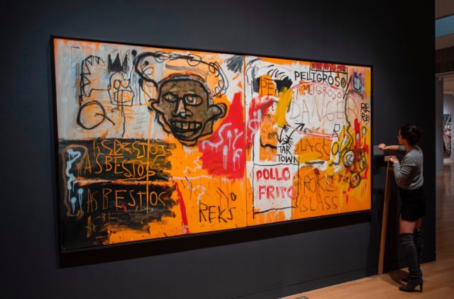 A Sotheby's employee hangs a name plate near Jean-Michel Basquiat's <em>Untitled (Pollo Frito)</em> on November 2, 2018, at Sotheby's Auction house in New York