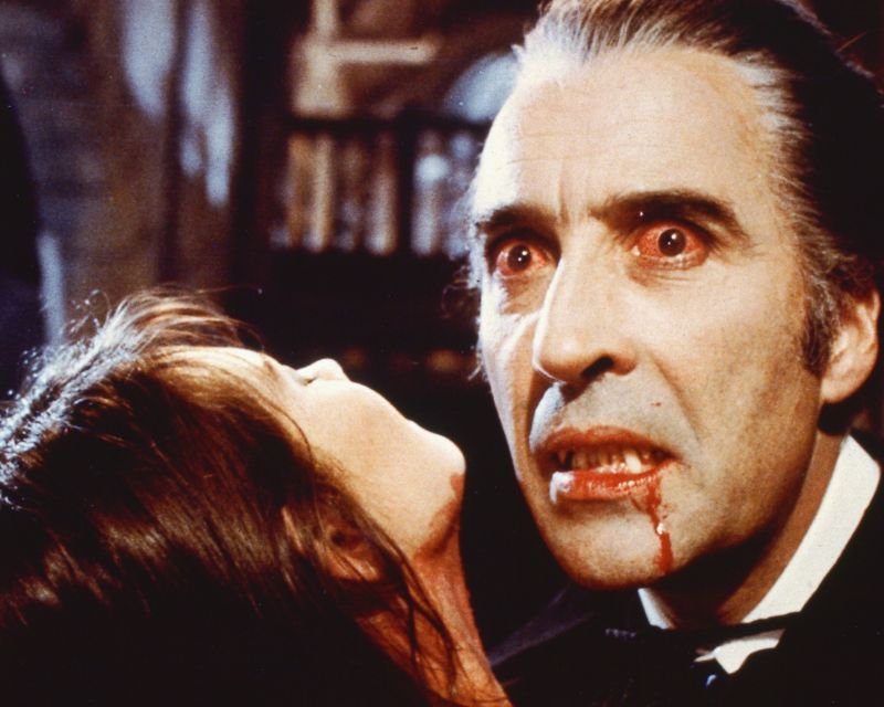 Still image from a Hammer horror film in which a vampire (Christopher Lee) sucks blood from an attractive female victim.