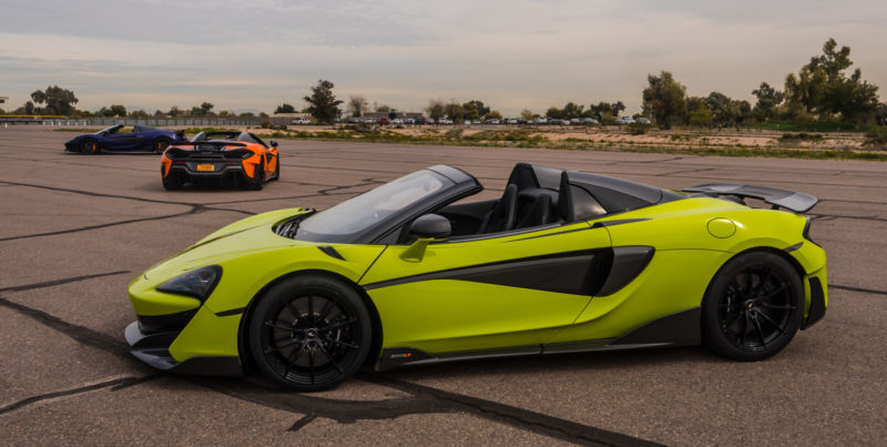 A supercar sits in a parking lot beneath an overcast sky.