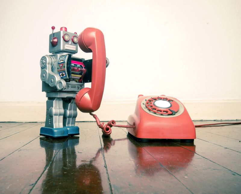 Illustration of a toy robot using a rotary telephone.