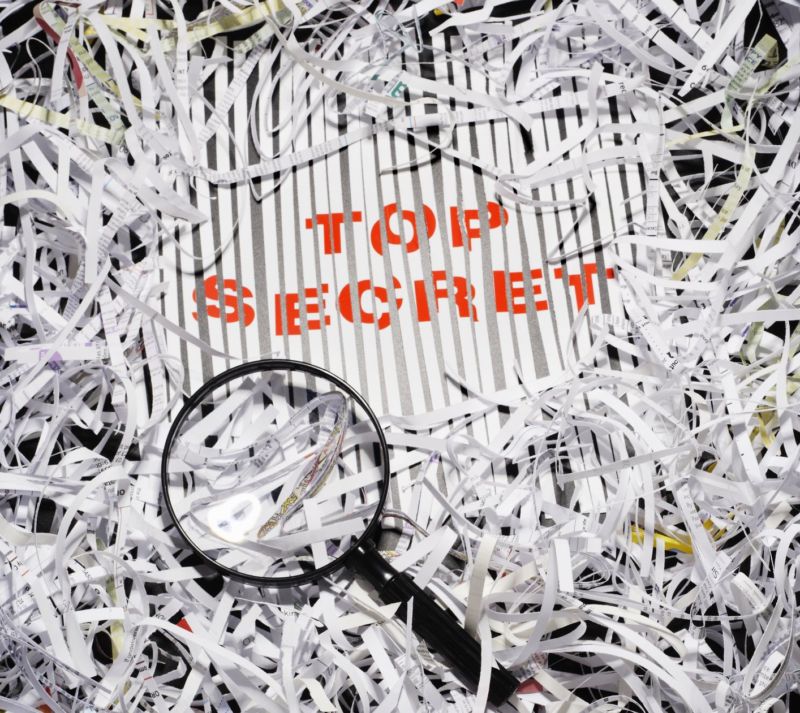 Shredded documents with a magnifying glass and the words, 