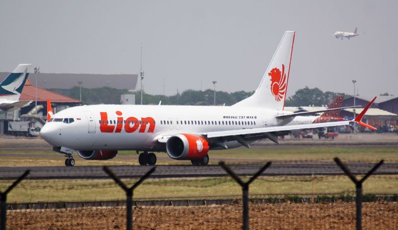 A passenger jet emblazoned with Lion Air logos taxis down a runway.