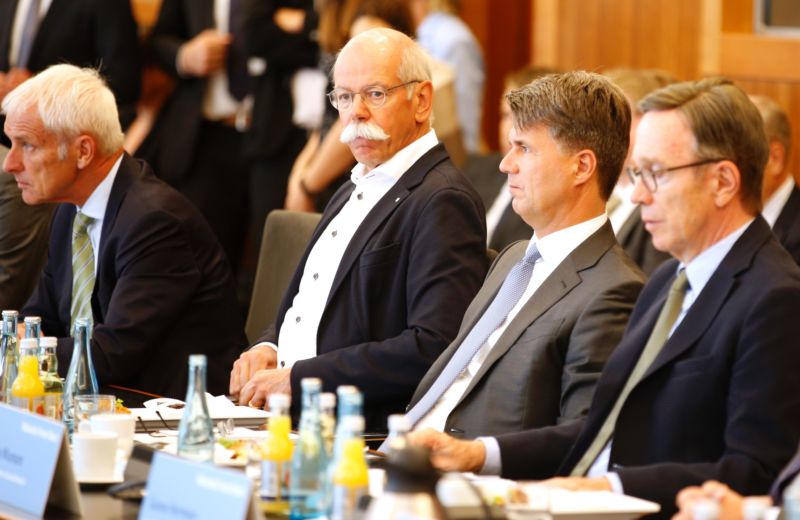 Four German auto executives sit at an event.