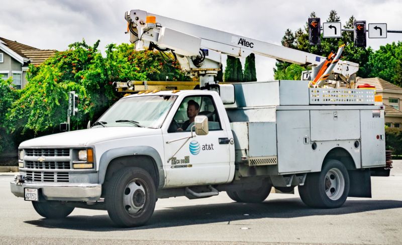 AT&T service truck driving on a street in a residential neighborhood.