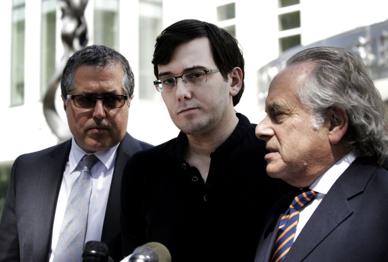 Three men stand behind microphones.