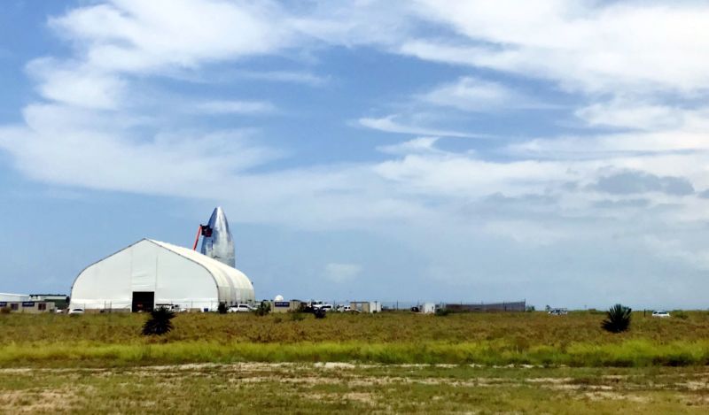 The nose cone of Starship Mk1 peeks out from behind SpaceX facilities in Boca Chica on July 24. 