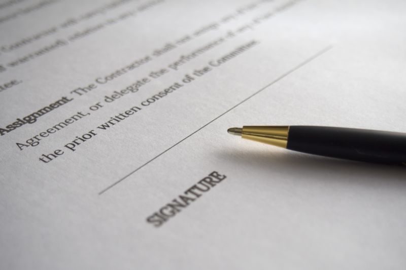 Extreme closeup of a pen next to a signature line on a legal document