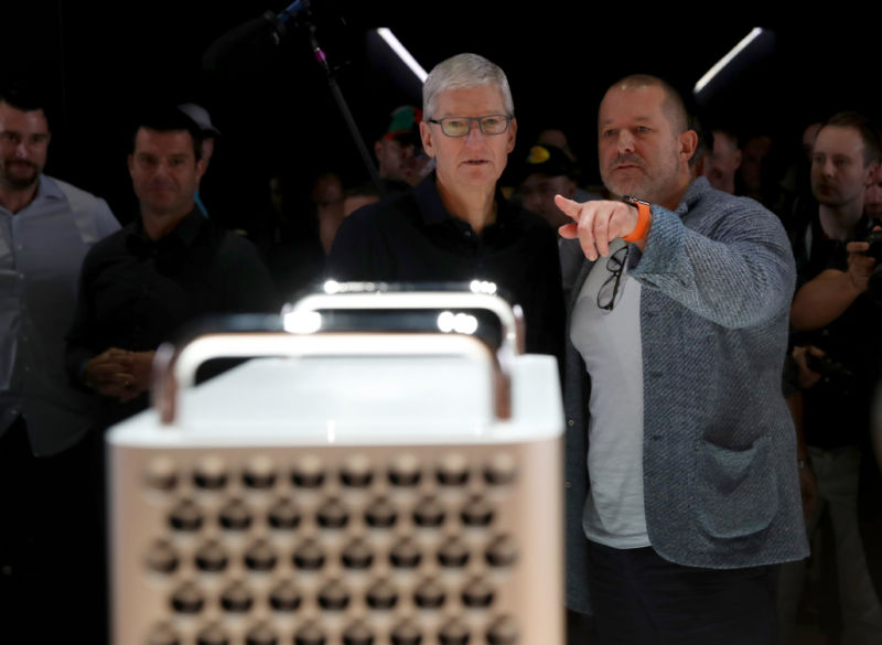 Two men in business casual examine a device that looks like a cheese grater.