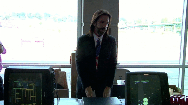 Mitchell stands behind footage of his claimed 1.06 million point <em>Donkey Kong</em> game at a 2010 press conference (click for slow motion replay that seems to show a MAME screen transition).