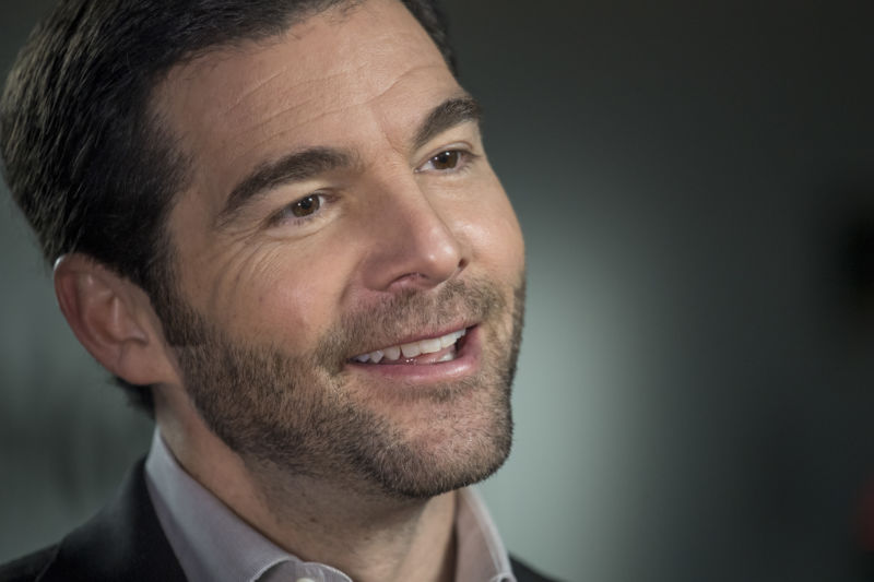 A smiling man in an open-collar suit.