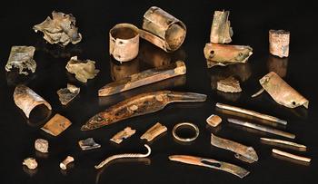 Color photo of bronze tools and scraps on a black background.