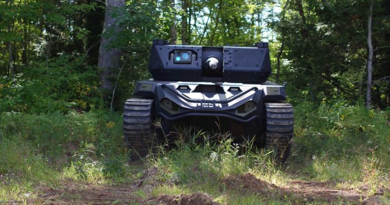 A uncrewed tank rolls through a forest.