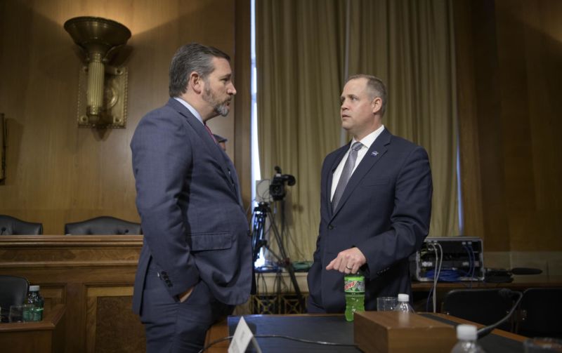 Two men in suits talk to each other.