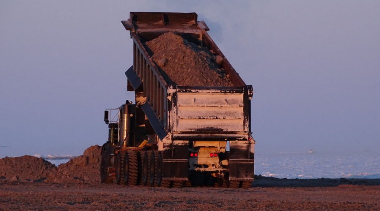 A dump truck is on the verge of emptying its contents.