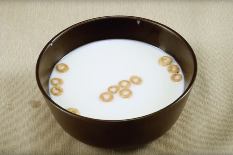 Image of a bowl of milk with a handful of Cheerios floating in it.