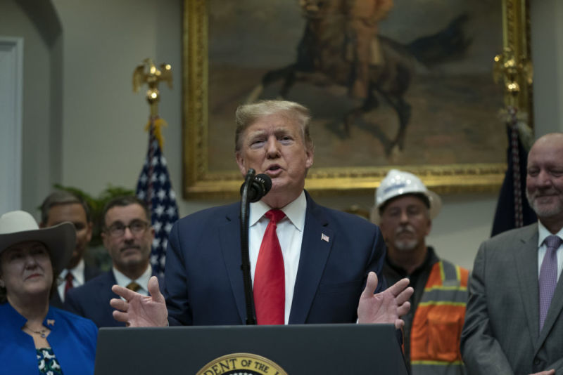 President Trump gesturing while speaking in front of a small group of supporters.