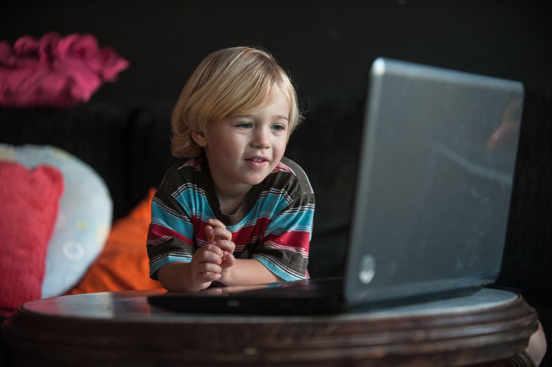 A young child watches a laptop computer. 