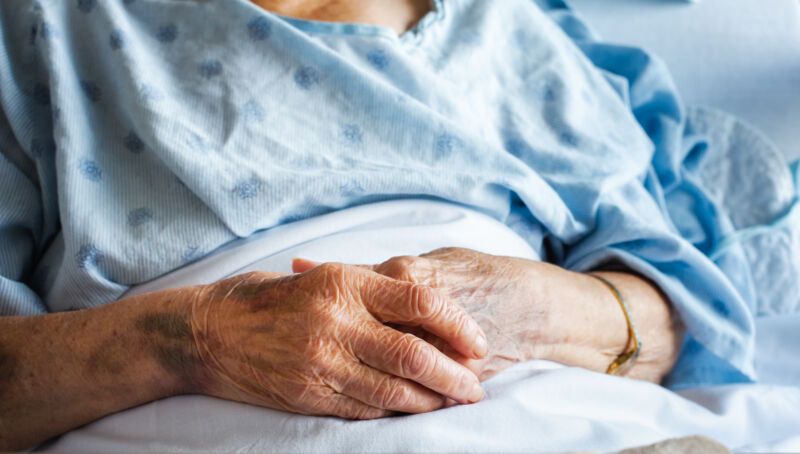 Closeup photograph of the hands of an old woman in bed.