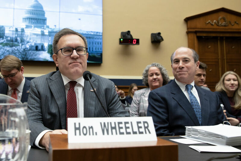 Image of two men sitting behind a large desk.