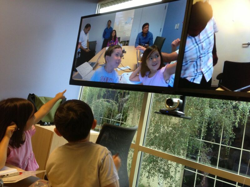 Children take part in a video conference on a large TV.