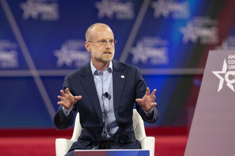 FCC Commissioner Brendan Carr speaking at a conference and gesturing with his hands.