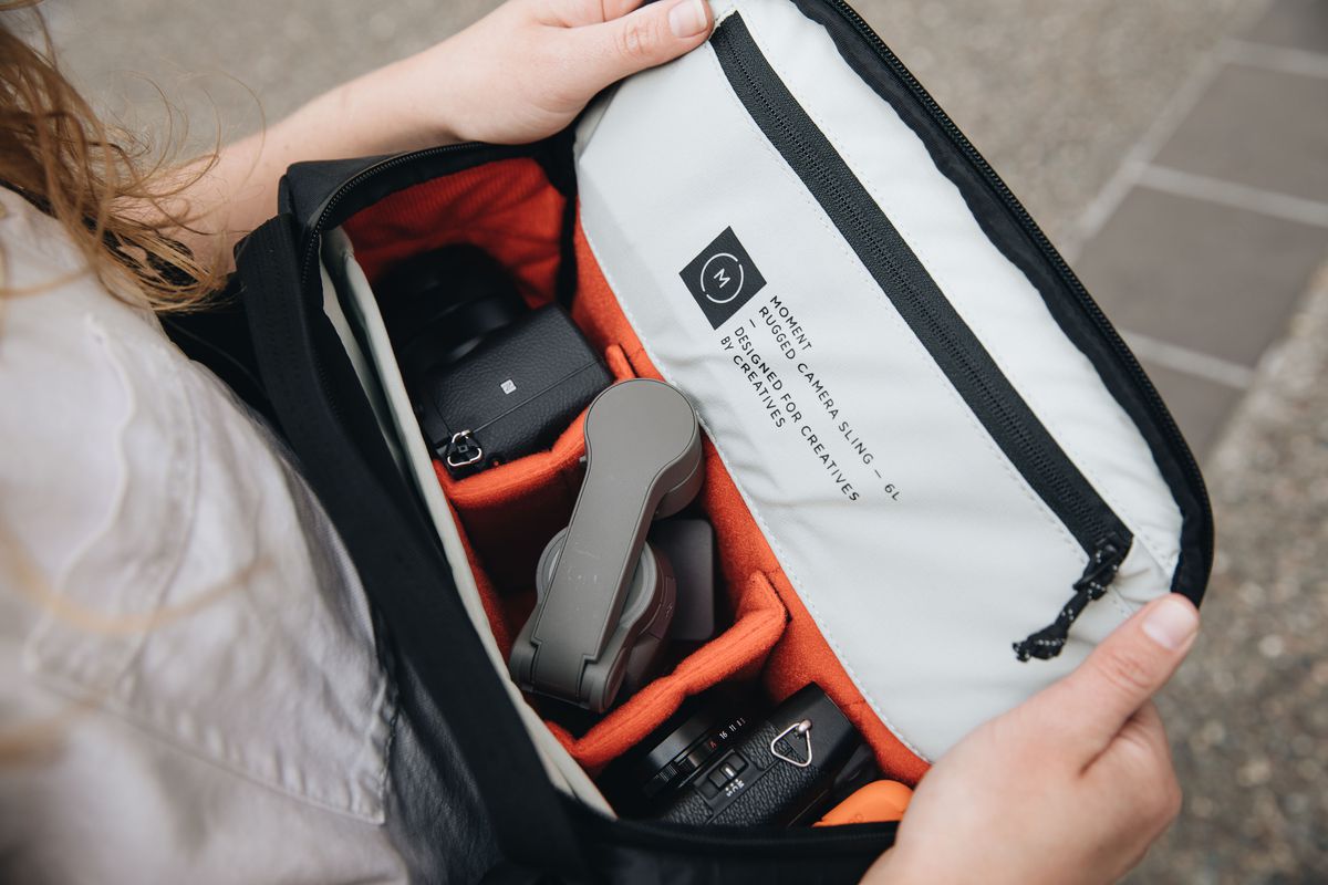 A Moment Rugged Camera Sling bag with its top open showing the interior.