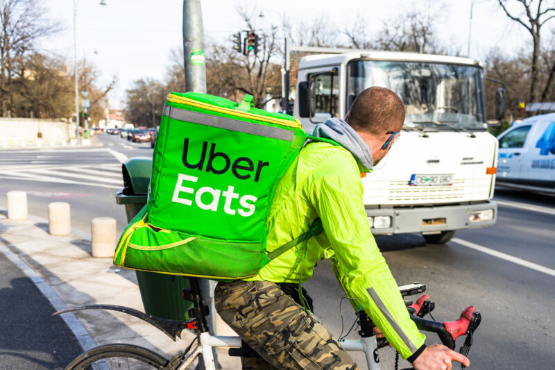 Young man on a bike with Uber Eats logo delivering food in Bucharest, Romania, 2020