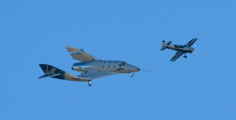 Giant airplane flies next to smaller spacecraft.