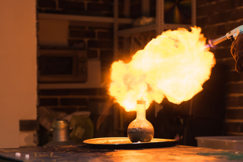 Lab technician setting fire to a ball with hydrogen blowtorch.