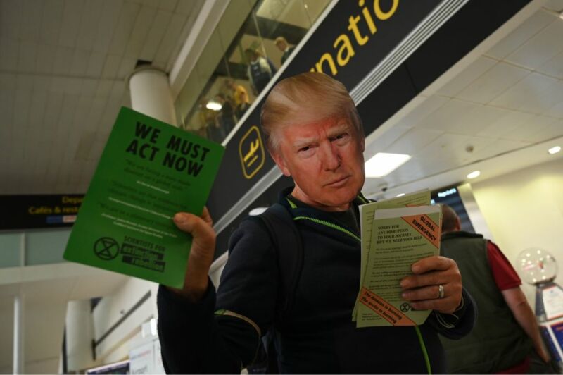 A climate activist wearing a mask of US President Donald Trump hands out leaflets at a protest action during the eleventh day of demonstrations by the climate change action group Extinction Rebellion, at Gatwick Airport, in Crawley, south of London on October 17, 2019. Activists from the environmental campaign group Extinction Rebellion have vowed to challenge a blanket protest ban imposed by the London police. (Photo by Glyn KIRK / AFP) (Photo by GLYN KIRK/AFP via Getty Images)