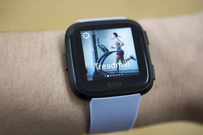 Fitbit Versa smartwatch on a person's wrist with the treadmill activity option on the screen.