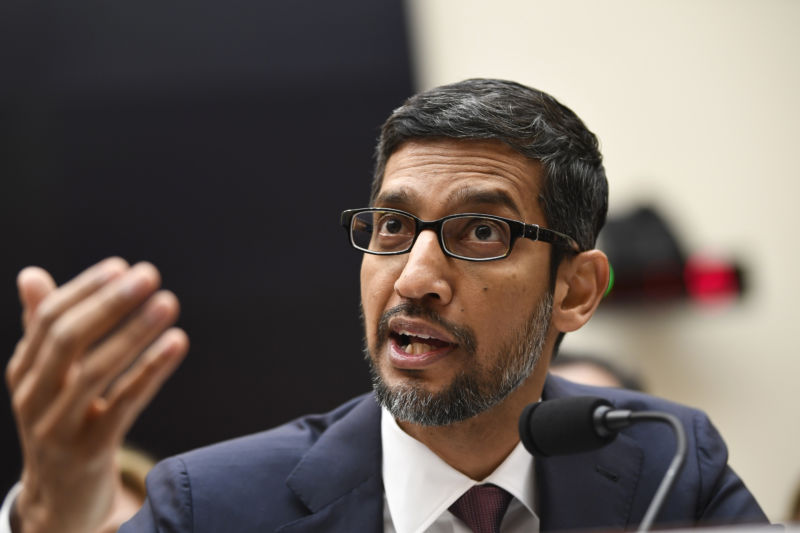 A serious man in a suit speaks into a microphone.