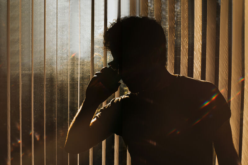 Stock photo of a shadowy man using a smartphone.