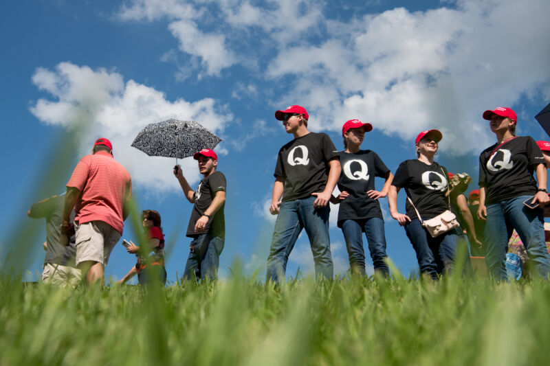 A cluster of Trump supporters, sporting Q-emblazoned T-shirts and the campaign's signature red MAGA hats, waiting in line to get into a rally in Tennessee in 2018.