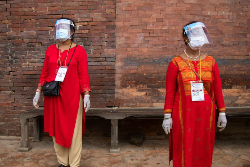 Image of two women wearing both face masks and face shields.