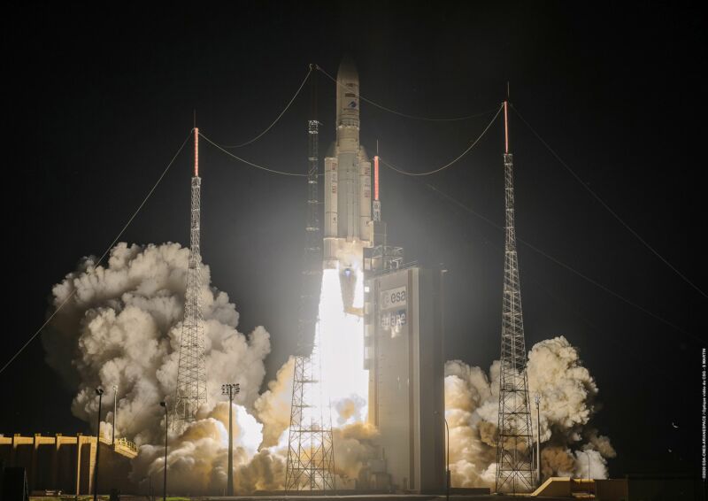 A rocket lifts off at night amidst flame and smoke.