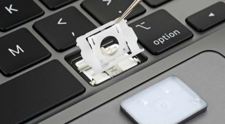 Extreme close-up photograph of a laptop keyboard being disassembled.