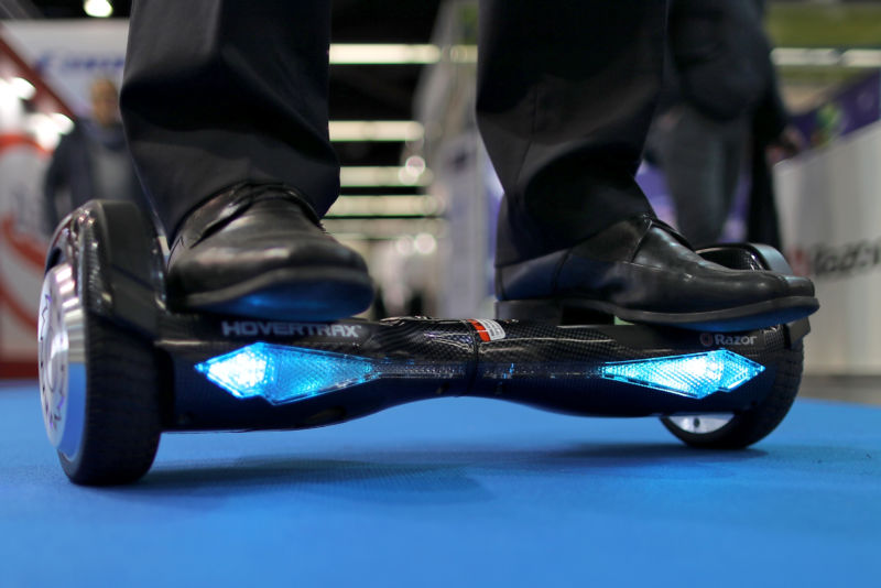 Close-up photograph of feet on hoverboard on institutional floor.