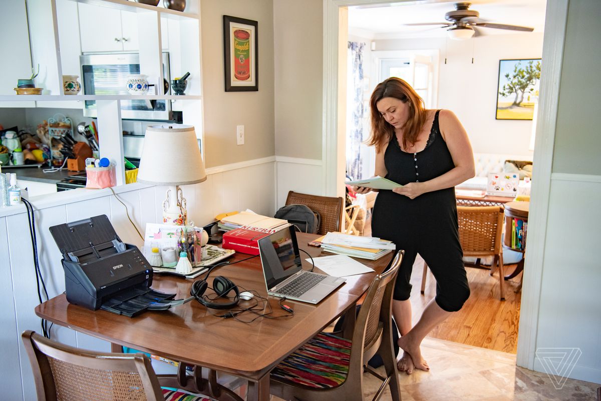 Sarah Owings stands at a table and work desk in her home. 