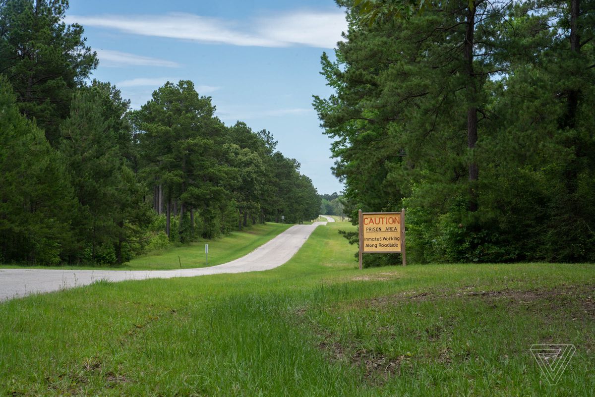 A small sign on a rural road reads “Caution prison area. Inmates working along roadside.”