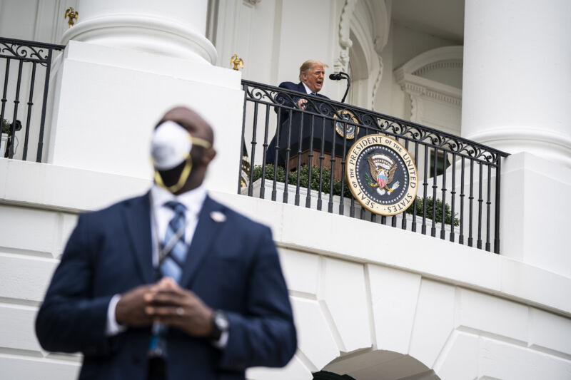 A member of the United States Secret Service wearing a face mask stands guard as President Donald J. Trump speaks to supporters from the Blue Room balcony during an event at the White House on Saturday, Oct. 10, 2020 in Washington, DC. 