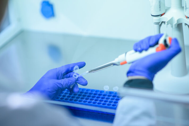 A researcher in protective gear fills vials.